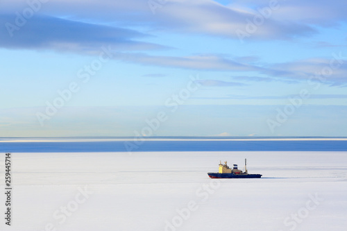Icebreaker among the ice. Maritime navigation in the north. Cold winter weather. Lonely ship and sea spaces. Nagaev Bay, Sea of Okhotsk, Magadan, Far East of Russia.