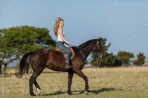 A gorgeous blonde cowgirl riding horse © jacojvr