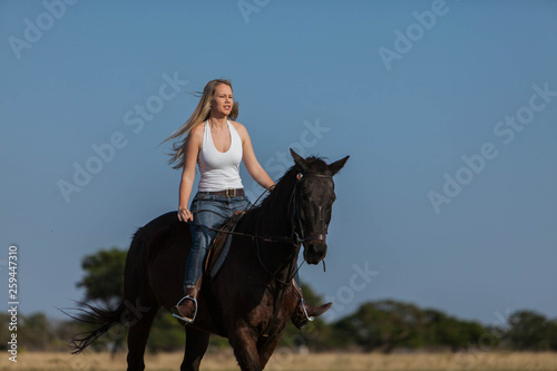 A gorgeous blonde cowgirl riding horse