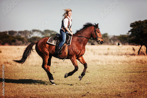 Attractive young blonde woman riding her horse