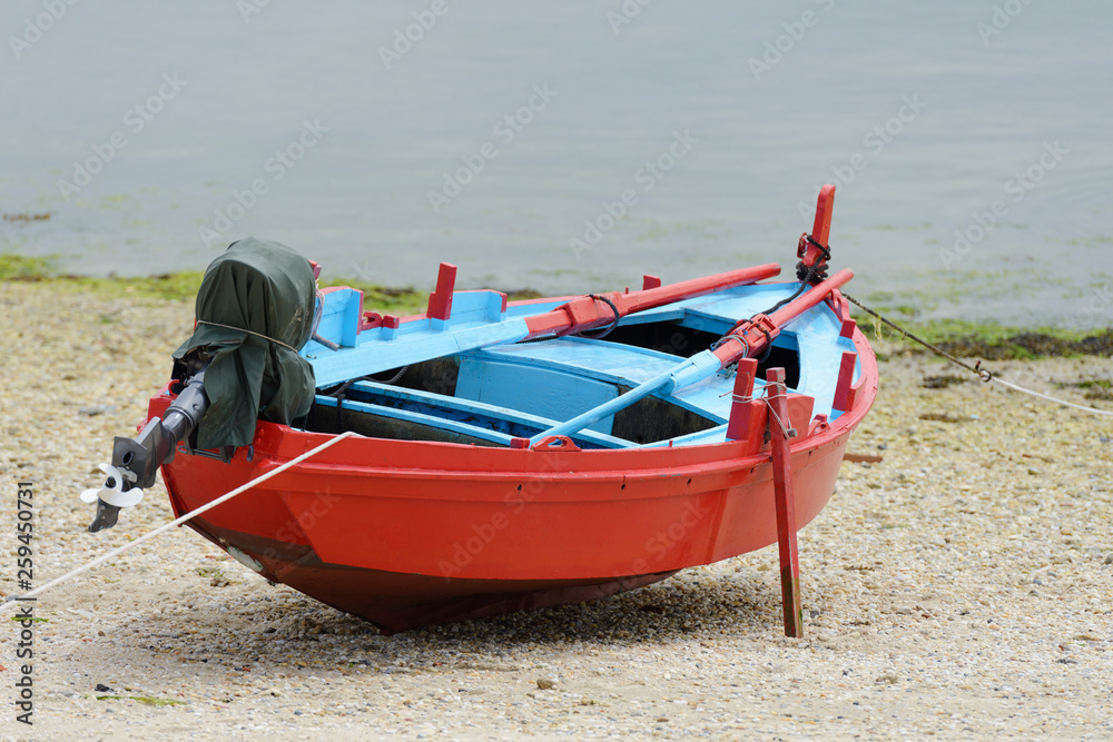 Fototapeta premium red wooden fishing boat moored on the shore