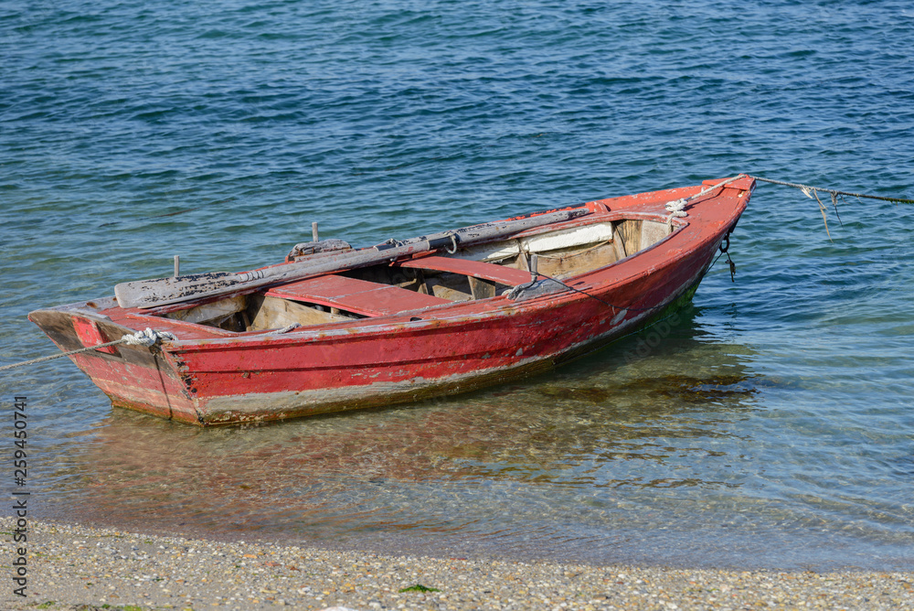red wooden fishing boat moored on the shore