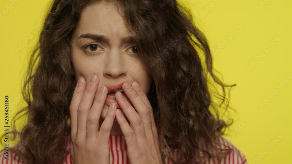 Afraid woman face with open mouth touching face with hands on yellow background Afraid woman face with open mouth touching face with hands on yellow background