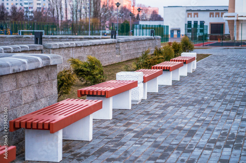 New benches made of metal and wood. A place to relax in the park. White trashcan of concrete.
