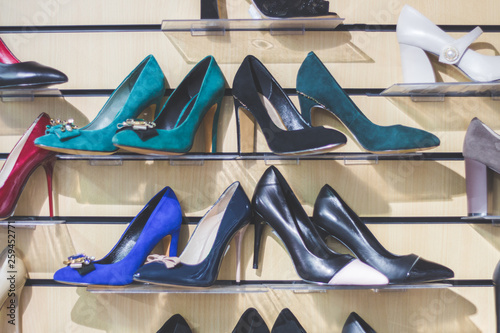 Classic women's shoes of dark colors on the store shelf. Blue, green and black shoes with high heels.