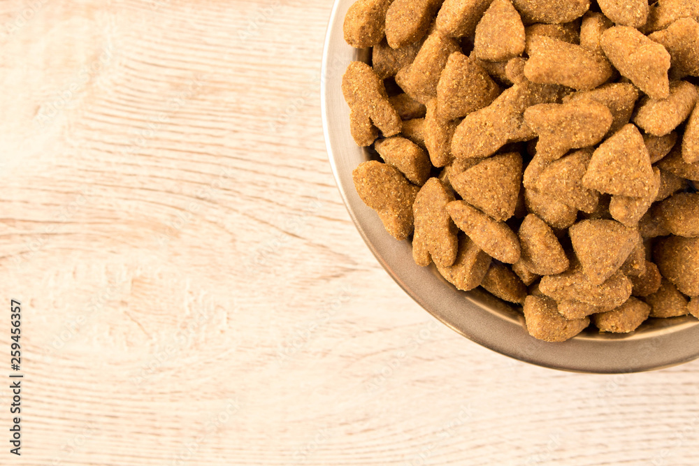 Bowl with dog food on a wooden table. Close up. Bowl with dog food on a wooden table. Close up.