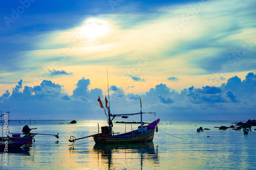 Fishing boat in the sea, sunset and silhouettes of wooden boats