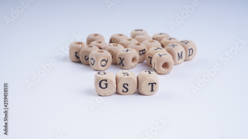 GST inscription on wooden alphabet over white background with selective focus