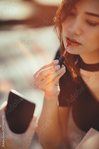 sexy woman making make-up woman applying lipstick outdoors.retro color