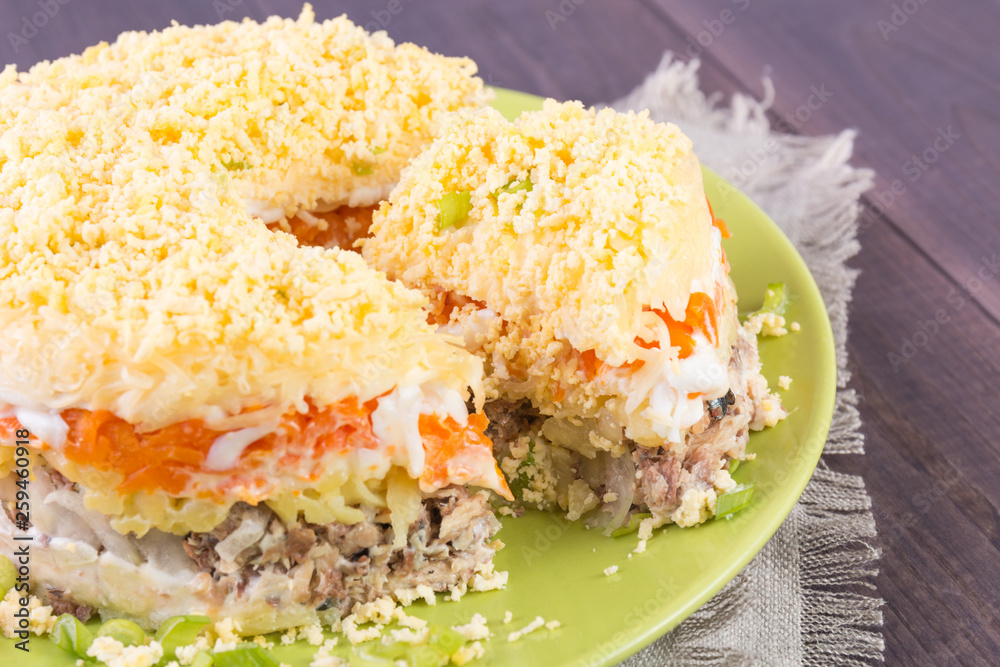Mimosa canned fish salad layers in the shape of a circle with a portion. Angle view Mimosa canned fish salad layers in the shape of a circle with a portion. Angle view