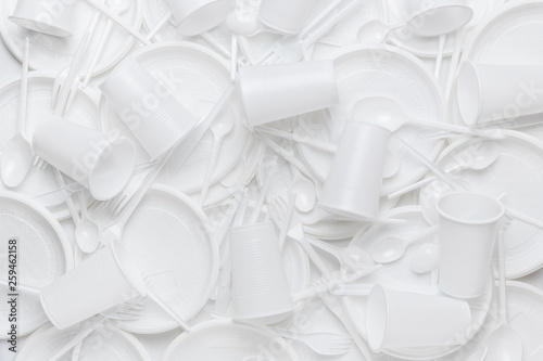 White disposable plastic tableware. Plastic plates, сups, forks, spoons, knives. Abstract background of clean white dishes.