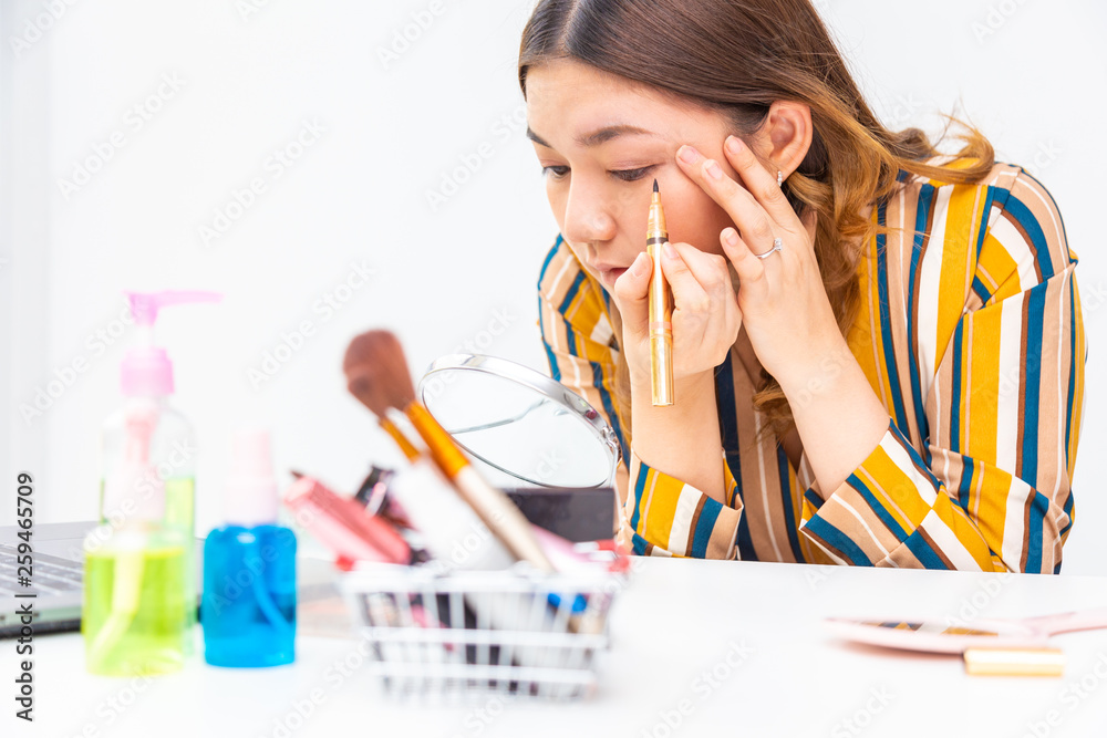 Beautiful young Asian woman putting her make up on Beautiful young Asian woman putting her make up on