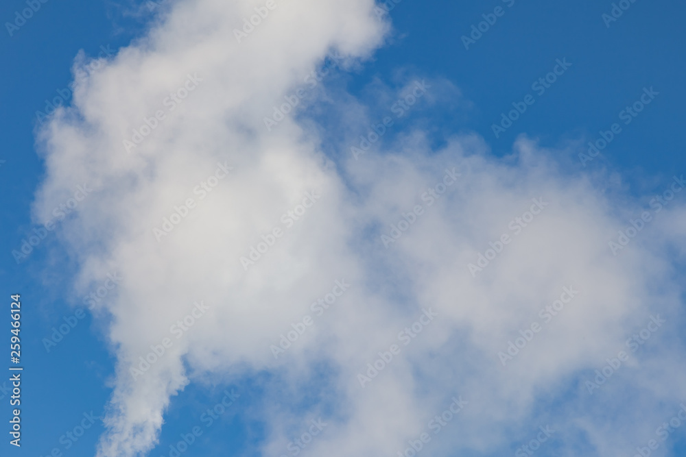 White harmful smoke coming out of the red-and-white pipes with mobile communication antennas at a factory in the city center against the background of a clear blue sky. Environmental problems. White harmful smoke coming out of the red-and-white pipes with mobile communication antennas at a factory in the city center against the background of a clear blue sky. Environmental problems.