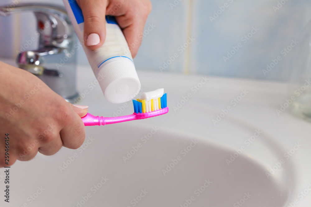 Hand applied toothpaste on toothbrush