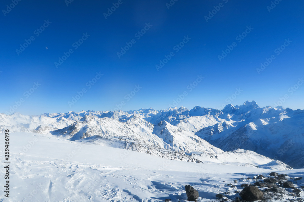 Moon above the mountain ridge of Caucasian Mountains in the blue sky. Elbrus region Moon above the mountain ridge of Caucasian Mountains in the blue sky. Elbrus region