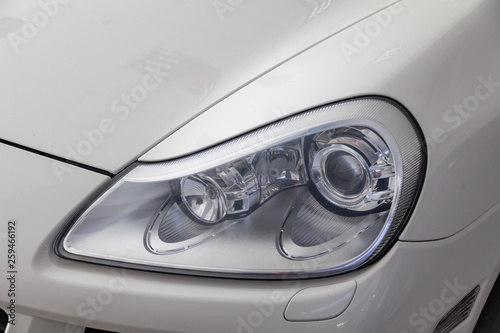 Front headlight view of car in white color after cleaning and detailing with washer before sale.