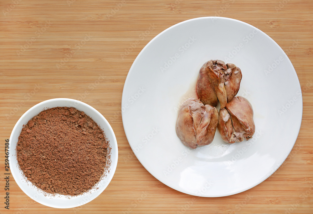 Boiled chicken liver in white plate and Mashed boil chicken liver in bowl on wooden board background. Boiled chicken liver in white plate and Mashed boil chicken liver in bowl on wooden board background.