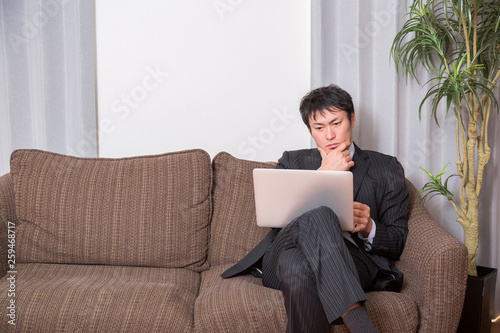 ソファでPCを開く男性（考える）