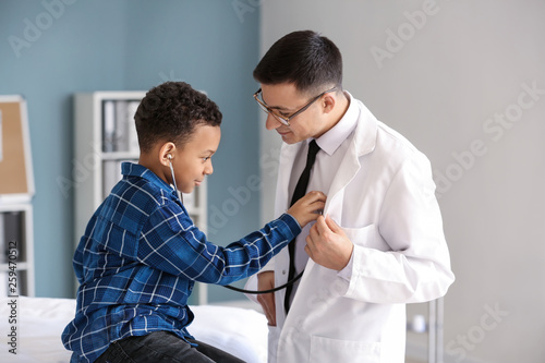 African-American boy playing with stethoscope at pediatrician's office