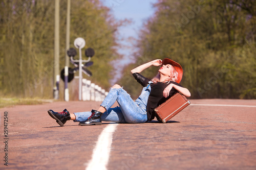 Beautiful traveling woman with retro suitcase on the road 