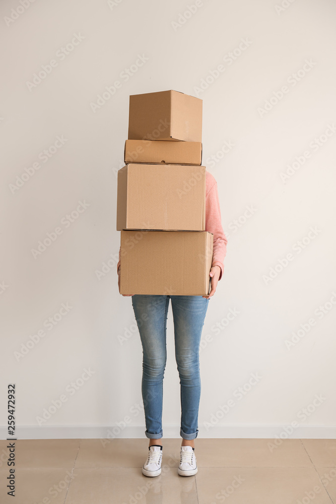 Woman with moving boxes near light wall in room Woman with moving boxes near light wall in room