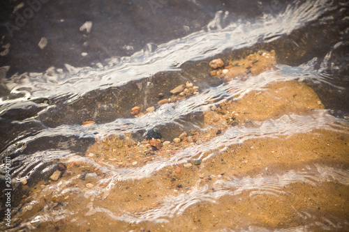 Background water. Asphalt and sand. Stream of water over the asphalt. Beautiful sea background with sand. Fine sand under water. Water texture Waves on the water. Different wavelength. The laws of phy photo