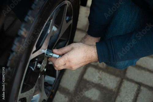 Man Unscrew the nuts to remove and change the wheel of a car © margo1778