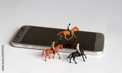 Photography Three miniature horses with riders and a smartphone.