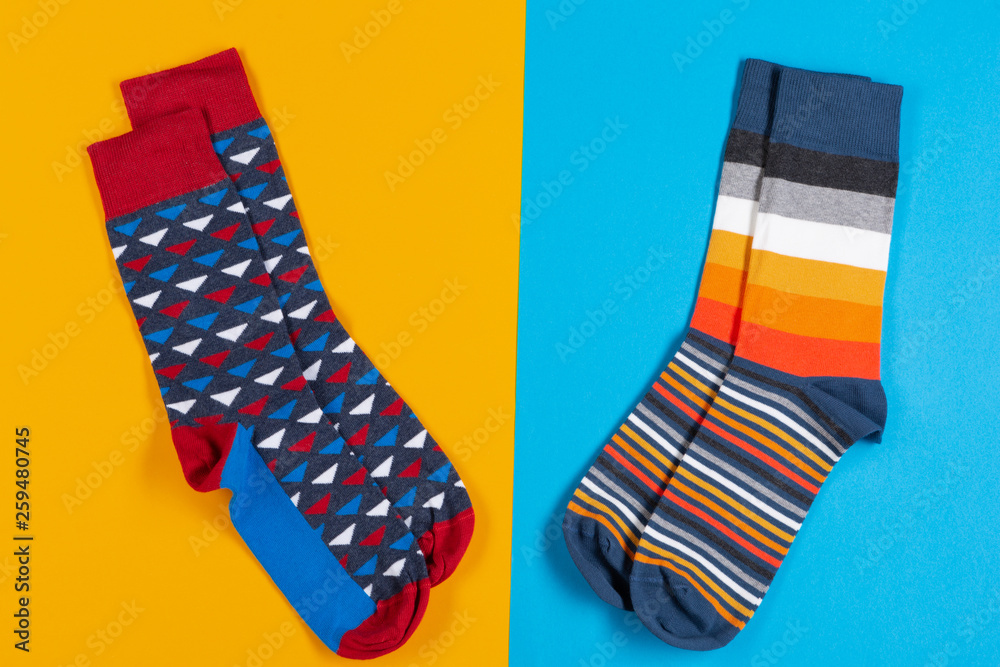 two pairs of colored unisex socks lie on a blue and yellow background, concept two pairs of colored unisex socks lie on a blue and yellow background, concept