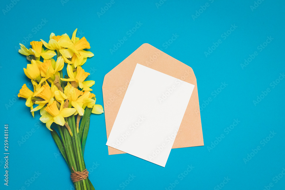 Fresh bouquet of narcissus flowers and the envelope with the letter on a blue background. minimalism Fresh bouquet of narcissus flowers and the envelope with the letter on a blue background. minimalism