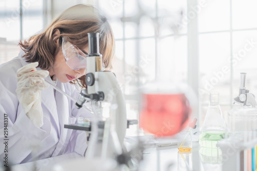 A young Asian woman scientist working in laboratory with test tube microscope and solutions.