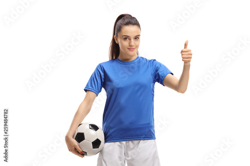Female football player holding a ball and making a thumb up sign