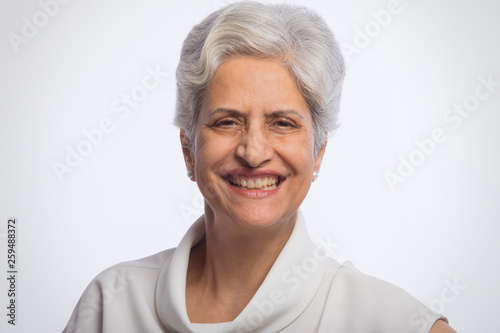 Portrait of senior woman standing against white background 