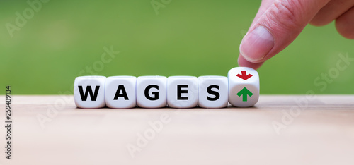 Symbol for a salary increase. Hand turns a dice and changes the direction of an arrow from down to up. Dice form the word "wages".