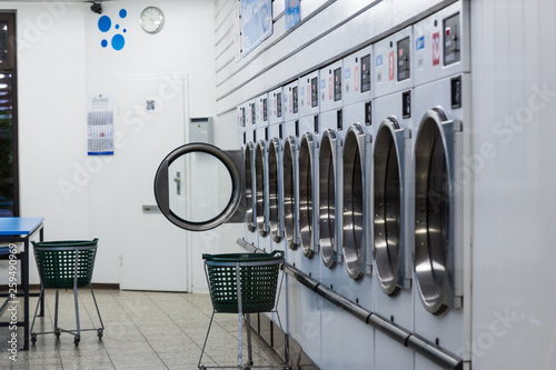 metallic laundry machines standing in a row and laundry baskets