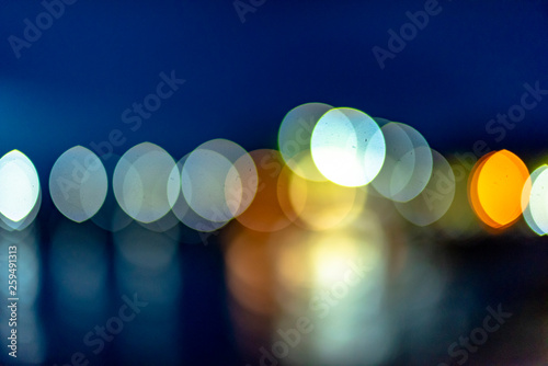 Night twilight blurred light gold bokeh reflecting on the sea surface water abstract background. © tar