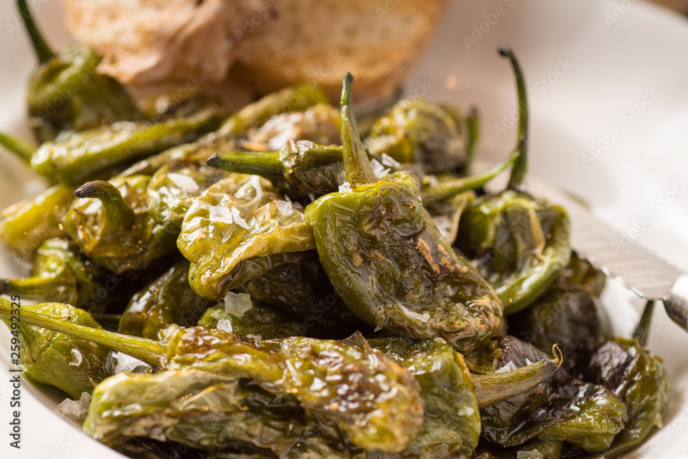 Green Padron Peppers with Crisp Bread in Rustic White Plate. Pimientos de Padrón. Green Padron Peppers with Crisp Bread in Rustic White Plate. Pimientos de Padrón.