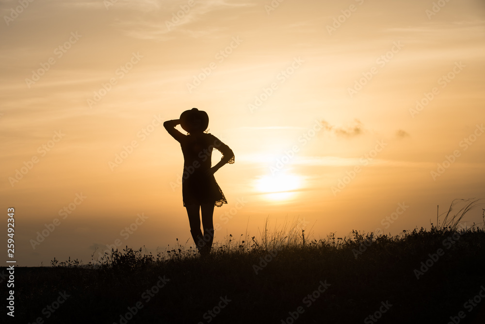 Woman with hat silhouette at sunset