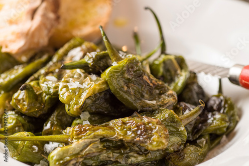 Green Padron Peppers with Crisp Bread in Rustic White Plate. Pimientos de Padrón.