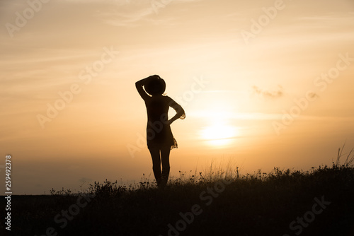 Woman with hat silhouette at sunset