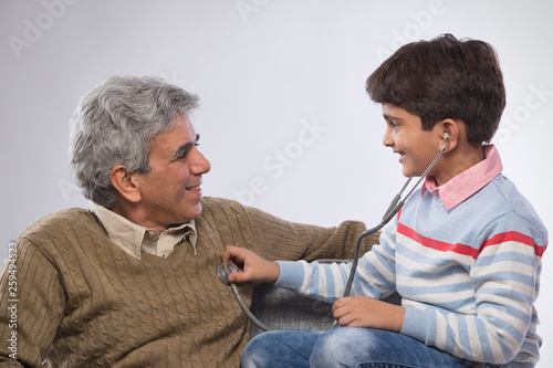 Grandson listening to grandfather's heartbeat with stethoscope	