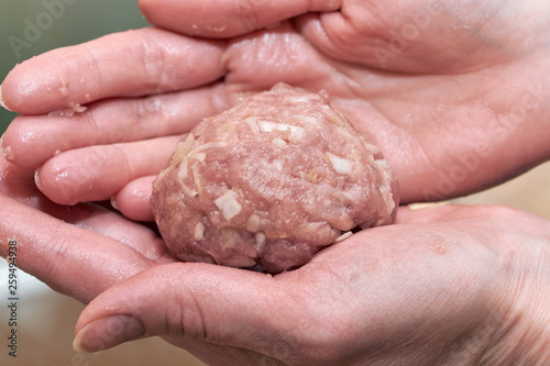 Raw round Patty of meat lies on the palms of women. Man sculpts cutlets of beef and pork. Home cooking or food. Shaping patties of raw ground beef. Healthy and good food. The cooking process.