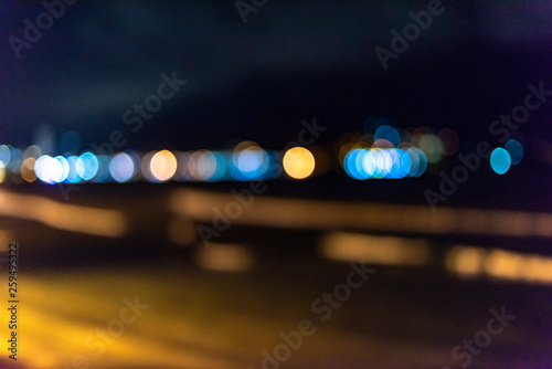 Night twilight blurred light gold bokeh reflecting on the sea surface water abstract background.