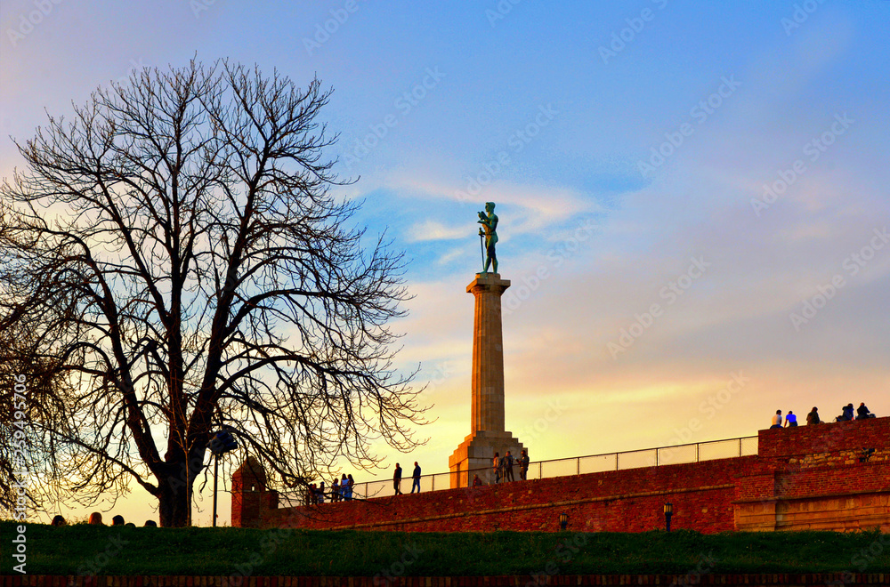  colorful blue sky with clouds and light on Viktor statue and people on the wall in Kalemegdan fortress in Belgrade Serbia