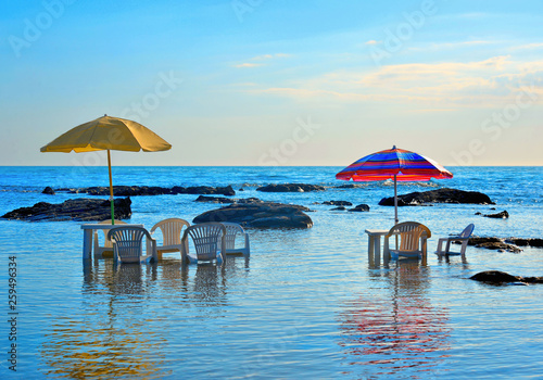 Tables and chairs immersed in the sea water under colorful umbrellas with the background of sea horizon  Agrigento Italy