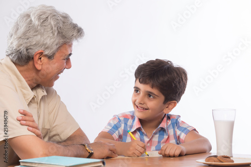 Grandfather helping grandson in homework 	