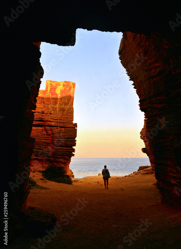 Lonely Young woman exit from Stone cave in Bue Marino beach in Favignana island on sunset in Sicily, Italy photo