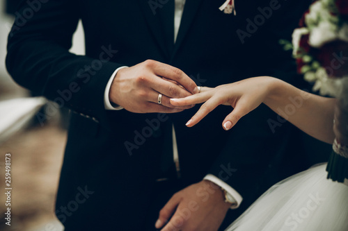 bride and groom exchanging wedding rings, putting on fingers during wedding ceremony in church. wedding couple