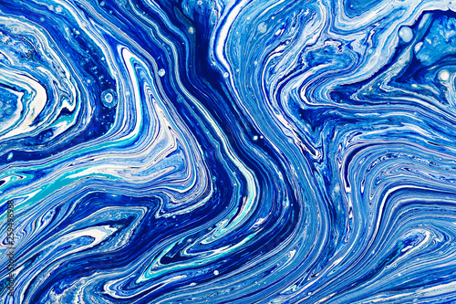 Hand painted background with mixed liquid blue, white, yellow paints. Abstract fluid acrylic painting. Applicable for packaging, invitation, textile, wallpaper, design of different surfaces