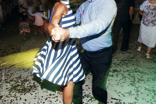 couple dancing, having fun at wedding reception party. guests at dance in restaurant, motion lights. joyful moments